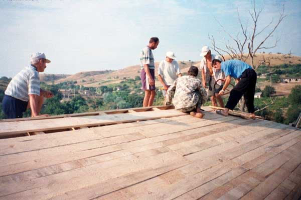 Săteni punând şindrila pe acoperiş